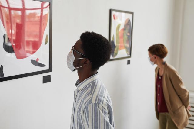 two young people of color looking at art on a wall in a gallery