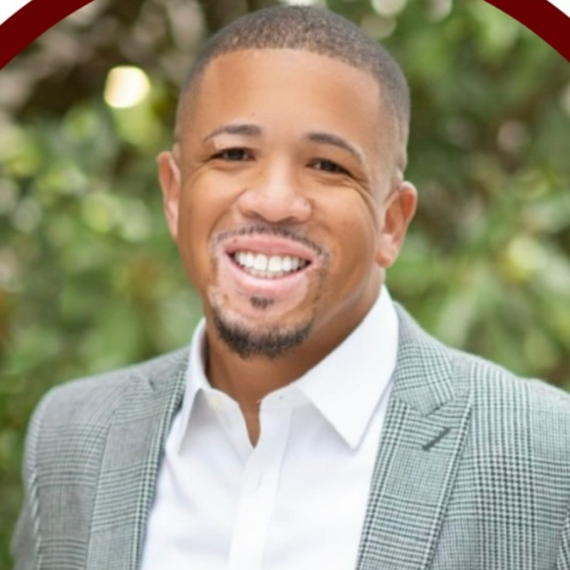 Headshot of Jarrett Brown smiling in a white button down shirt and blazer